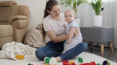 Annesinin kucağında oturan ve renkli oyuncaklara bakan sevimli, gülümseyen çocuk. Çocuk gelişimi, eğitim ve yaratıcılık kavramı