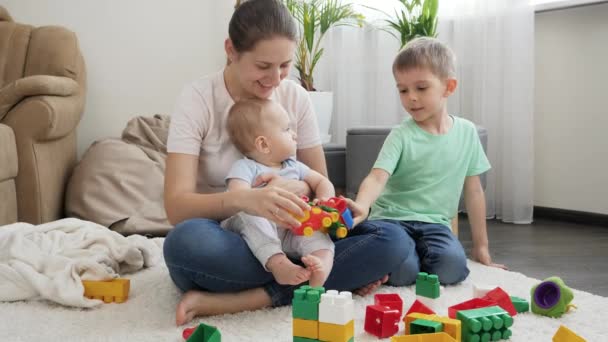 Glücklich lächelnde Familie mit Kindern auf Teppich im Wohnzimmer. Konzept der gemeinsamen Zeit der Familie und der Entwicklung der Kinder — Stockvideo