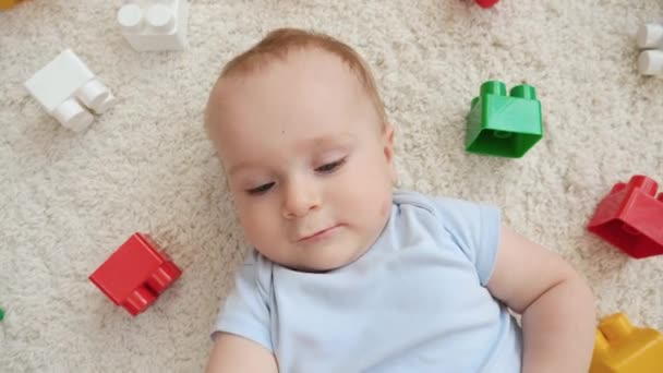 Zoom fora tiro de menino e montão de brinquedos no tapete na sala de jogos. Conceito de desenvolvimento infantil, educação e criatividade em casa — Vídeo de Stock