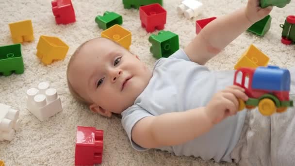 Portrait de mignon petit garçon qui s'amuse avec des jouets sur le tapis dans la palyroom. Concept de développement, d'éducation et de créativité des enfants à la maison — Video