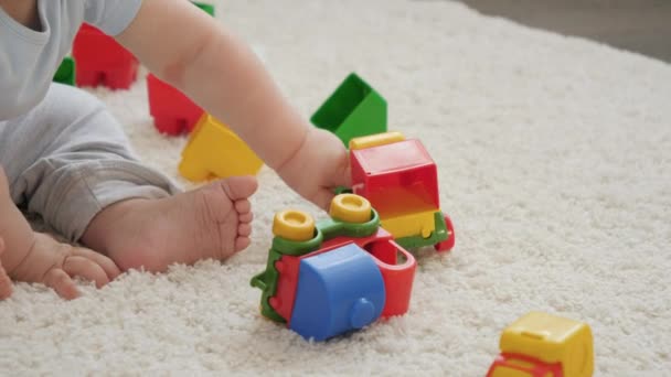 Närbild av bab hand spela och rullande färgglada leksaksbilar på matta i lekrummet. Begreppet barns utveckling, utbildning och kreativitet i hemmet — Stockvideo