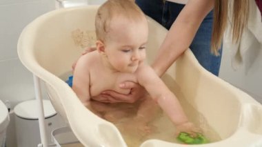 Oyuncak oynayan ve plastik çocuk banyosunda su sıçratan neşeli gülümseyen çocuk. Çocuk hijyeni, sağlık ve ebeveynlik kavramı.