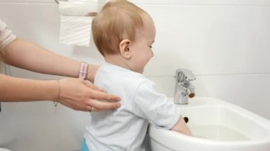Tuvalette duran ve su sıçratan sevimli erkek bebek portresi. Evde çocuk gelişimi, eğlence ve eğitim kavramı.