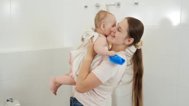 Lächelnde Mutter nimmt ihr Baby aus der Badewanne und wischt mit Handtuch. Konzept der Kinderhygiene, Gesundheitsfürsorge und Kindererziehung. — Stockvideo