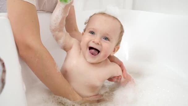 Niño divertido con espuma de jabón en la cabeza jugando en el baño con barcos de juguete y barcos. Concepto de higiene infantil, atención sanitaria y desarrollo en el hogar — Vídeo de stock