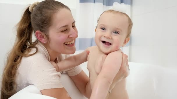 Smiling baby boy washing in bath with foam with mother. Concept of children hygiene, healthcare and development at home — Stock Video