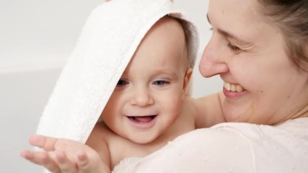 Portret uśmiechniętej młodej matki wycierającej mokre włosy i głowę synka po kąpieli. Pojęcie higieny dzieci, opieki zdrowotnej i opieki rodzinnej w domu — Wideo stockowe