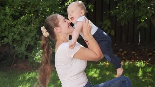 Glædelig grinende baby dreng med mor have det sjovt og lege i haven. Forældre, familie, børns udvikling og sjov udendørs i naturen. – Stock-video