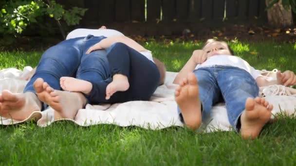 Zbliżenie dzieci i matek stóp leżących na trawie w parku lub ogrodzie. Rodzicielstwo, rodzina, rozwój dzieci i zabawy na świeżym powietrzu w przyrodzie. — Wideo stockowe