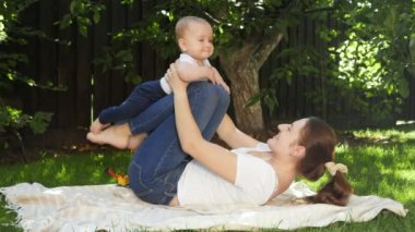 Mutlu gülümseyen ve gülen bir anne ve bahçede oynayan bir çocuk. Ebeveynlik, aile, çocuk gelişimi ve doğada eğlence..