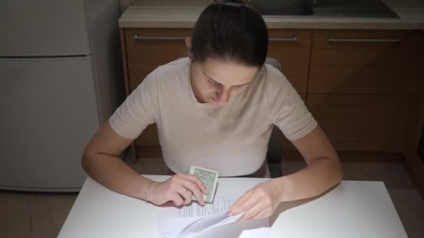 Wanita stres memiliki masalah keuangan duduk di dapur dan membaca dokumen pemberitahuan pajak. Konsep kesulitan keuangan, kebangkrutan, pajak dan pembayaran sewa. — Stok Video