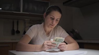 Stresli kadın geceleri mutfakta para sayıyor. Mali zorluklar, yoksulluk, iflas, vergiler ve kira ödemeleri kavramı.