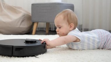 Küçük bir çocuğun robot elektrik süpürgesiyle oynarken portresi. Modern hayatta hijyen, ev aletleri ve robotlar kavramı.