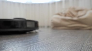 Evdeki ahşap zemini temizleyen robot elektrik süpürgesine yakın çekim. Modern hayatta hijyen, ev aletleri ve robotlar kavramı.