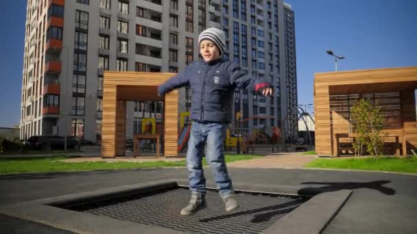 Menino alegre sorrindo enquanto saltava no trampolim no parque público. Conceito de desenvolvimento infantil, esportes e educação. — Vídeo de Stock