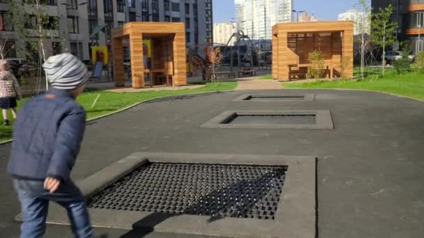 Feliz chico corriendo y saltando en camas elásticas en el palyground en el parque. Concepto de desarrollo infantil, deportes y educación. — Vídeos de Stock