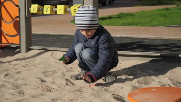 遊び場の公園でサンドピットで遊んでいる小さな男の子。子供の発達、スポーツ、教育の概念. — ストック動画