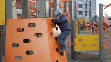 Neşeli çocuk bahçedeki çocuk parkına tırmanıp kayıyor. Çocuk gelişimi, spor ve eğitim kavramı.
