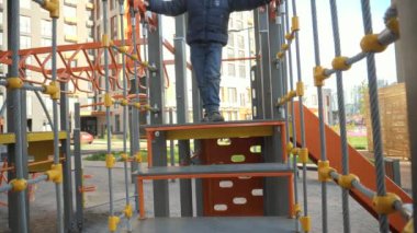 Mutlu gülümseyen çocuk, çocuk parkına tırmanıyor, iplerde yürüyor ve merdivenlerde yürüyor. Çocuk gelişimi, spor ve eğitim kavramı.