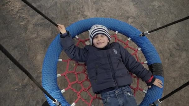 Leende glad pojke njuter svinga på rep swing i parken. Begreppet barnutveckling, idrott och utbildning. — Stockvideo