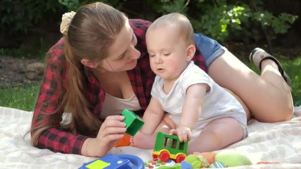 Liebevolle Mutter entspannt sich mit ihrem kleinen Sohn im Park und spielt auf dem Rasen. Konzept der kindlichen Entwicklung, der gemeinsamen Zeit der Familie und der Elternschaft. — Stockvideo