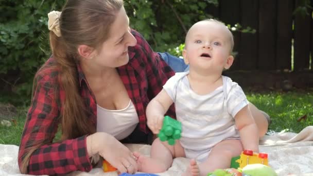 Bambino carino seduto sull'erba con la madre e giocare giocattoli. Concetto di sviluppo del bambino, famiglia che ha tempo insieme e genitorialità. — Video Stock