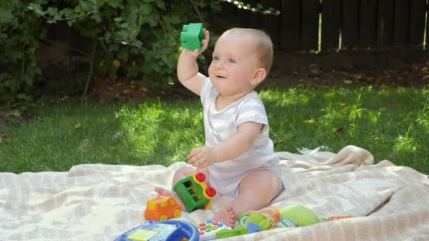 Schattige baby jongen spelen met speelgoed op gras in huis achtertuin. Concept van kinderontwikkeling, onderwijs en ontspanning in de buitenlucht. — Stockvideo