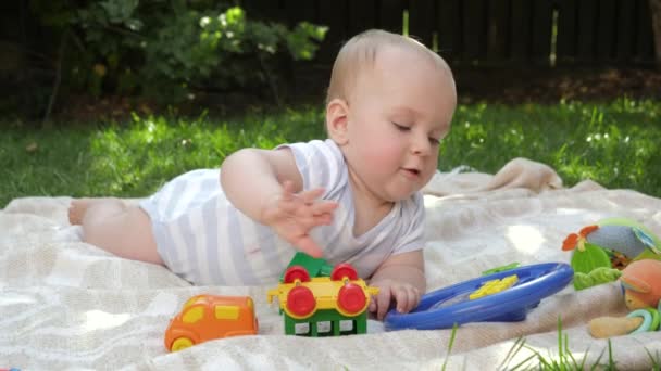 Portret van een lachende jongen die speelgoed speelt op de picknick in het park. Begrip "vroegtijdige ontwikkeling van het kind", "onderwijs" en "ontspannen buitenshuis". — Stockvideo