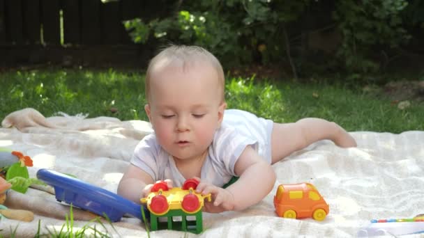 Cute 9 months old baby boy playing with toys on grass at backyard garden. Concept of child early development, education and relaxing outdoors. — Stock Video