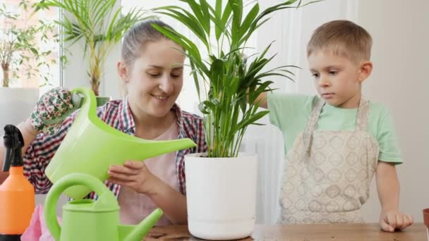 Jovem mãe com filho cuidando de plantas domésticas e regando-os com regador. Conceito de jardinagem, hobby, plantio em casa. — Vídeo de Stock