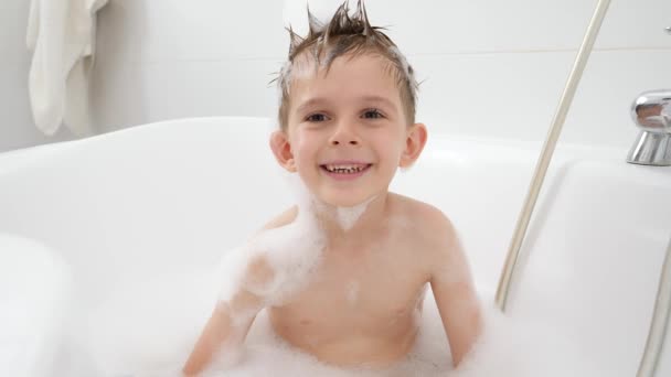 Buon ragazzo sorridente enjyoing lavaggio in bagno e giocare con schiuma di sapone. Concetto di hygine, sviluppo bambini e divertimento a casa — Video Stock