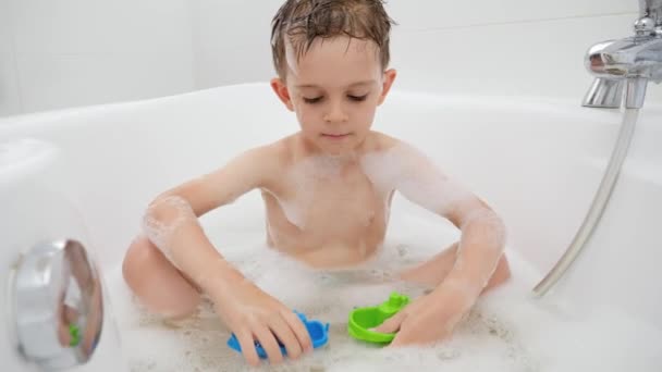 Ragazzo carino lavarsi in bagno e avere con giocattoli di plastica. Concetto di tempo in famiglia, sviluppo dei bambini e divertimento a casa — Video Stock