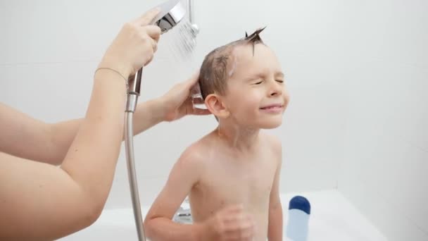 Junge Mutter hilft ihrem kleinen Sohn unter der Dusche im Badezimmer zu waschen. Konzept aus Hygiene, kindlicher Entwicklung und Spaß zu Hause — Stockvideo