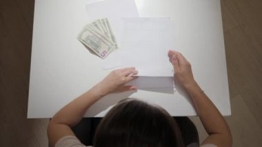 Stresli kadın finansal raporları okuyor ya da geceleri mutfakta ev kredisi borcu alıyor. Mali zorluklar, yoksulluk, iflas, vergiler ve kira ödemeleri kavramı.