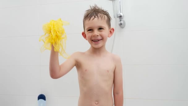 Felice ridente ragazzo che gioca con spugna gialla mentre si lava sotto la doccia in bagno. Concetto di hygine, sviluppo bambini e divertimento a casa — Video Stock