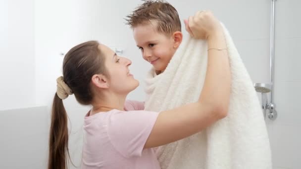 Fürsorgliche Mutter trocknet ihren Sohn mit Handtuch und umarmt ihn nach dem Baden. Konzept aus Hygiene, kindlicher Entwicklung und Spaß zu Hause — Stockvideo