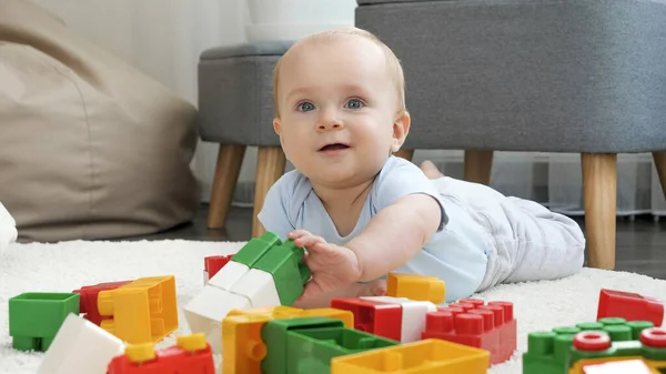 Porträtt av glada leende pojke leker med färgglada tegelstenar och block på golvet i vardagsrummet. Begreppet barns utveckling, utbildning och kreativitet i hemmet — Stockfoto