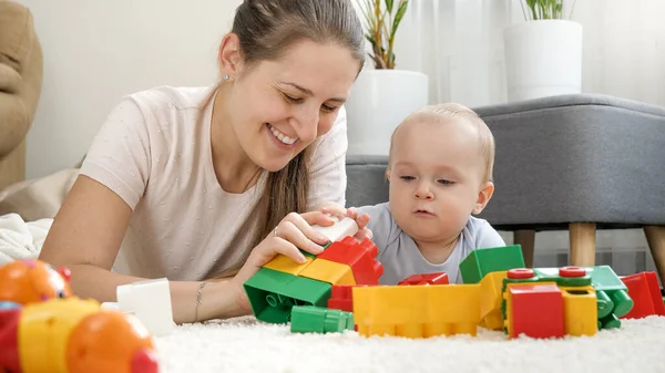 Pequeño niño con la madre jugando juguetes en la alfombra en la sala de estar. Concepto de desarrollo infantil, educación y creatividad en el hogar — Foto de Stock
