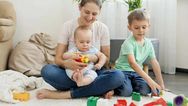 Szczęśliwa uśmiechnięta rodzina z dziećmi palącymi na dywanie w salonie. Pojęcie rodziny spędzającej razem czas i rozwoju dzieci — Zdjęcie stockowe