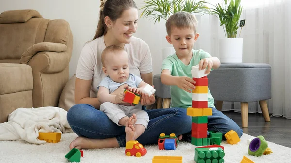 Счастливая семья строит высокую башню с игрушечными блоками и брикетами. Концепция семейного времяпровождения и развития детей — стоковое фото