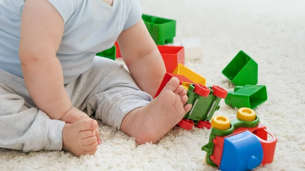 Närbild av bab hand spela och rullande färgglada leksaksbilar på matta i lekrummet. Begreppet barns utveckling, utbildning och kreativitet i hemmet — Stockfoto