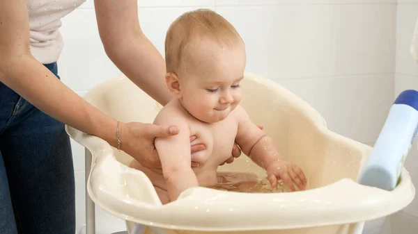 Alegre niño sonriente salpicando agua y jugando mientras se bañan con la madre. Concepto de higiene infantil, atención sanitaria y crianza de los hijos. — Foto de Stock