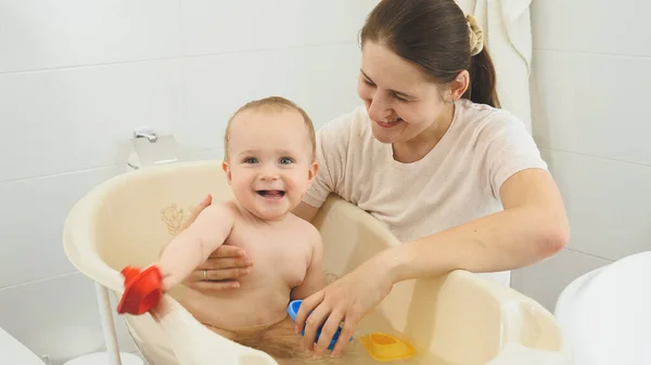 Feliz niño sonriente con la madre lavándose en el baño y jugando juegos — Foto de Stock