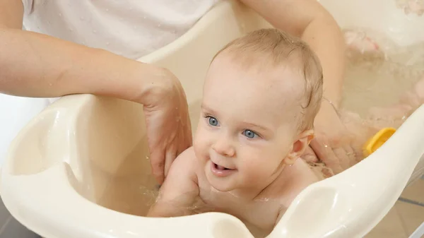 Lindo niño sonriente jugando y nadando en un pequeño baño en casa. Concepto de higiene infantil, atención sanitaria y crianza de los hijos. — Foto de Stock