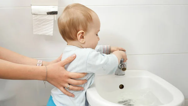 Boldog kisfiú játszik víz csapot bidében vagy WC-ben a fürdőszobában — Stock Fotó