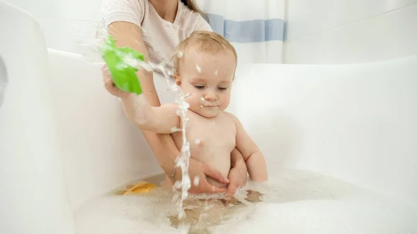 Niño sonriente bañándose con espuma y jugando con botes de juguete. Concepto de higiene infantil, atención sanitaria y desarrollo en el hogar — Foto de Stock