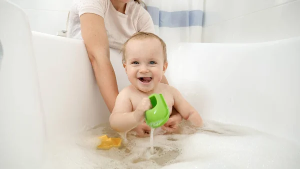 Feliz niño sonriente jugando con juguetes y lavándose en el baño — Foto de Stock