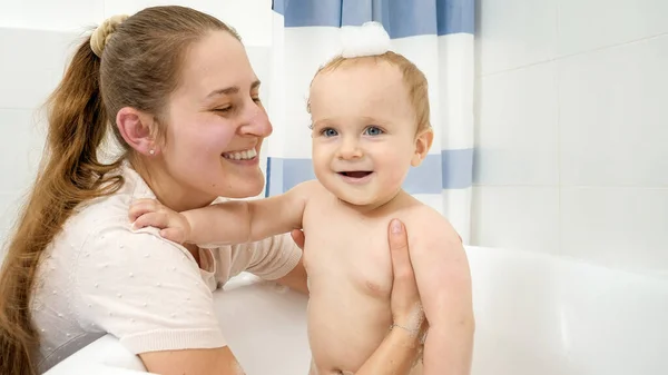 Portrait de mère souriante heureuse avec bébé garçon ayant bain de savon. Concept d'hygiène, de santé et de développement des enfants à domicile — Photo