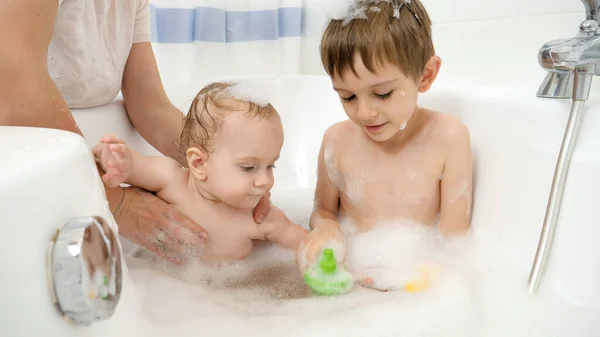 Dos niños sonrientes felices lavándose en el baño y jugando juguetes — Foto de Stock