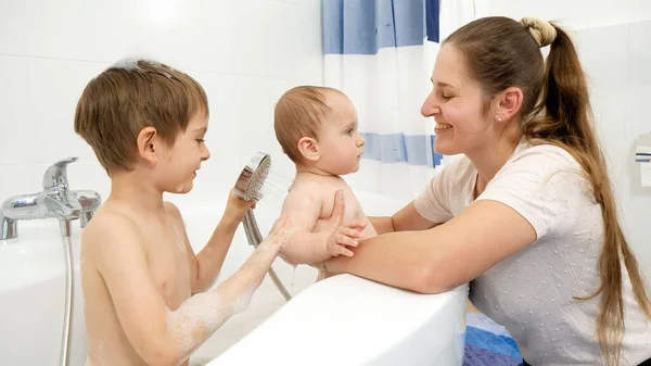 Усміхнений хлопчик з матір'ю миє хлопчика в ванні під душем — стокове фото